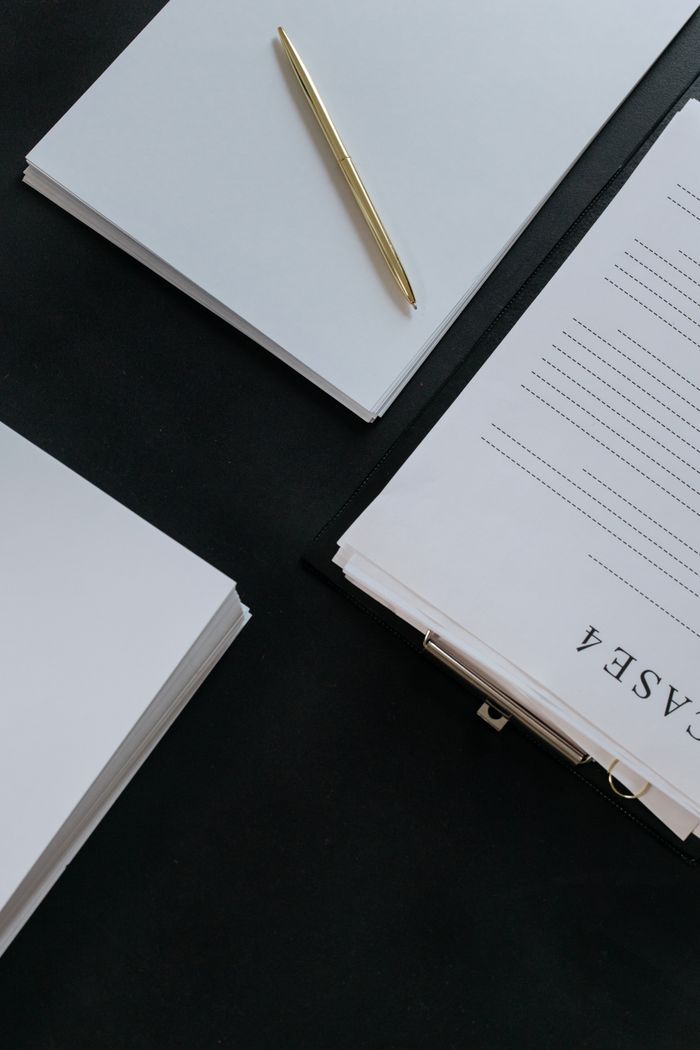 Products Stylish arrangement of papers and a gold pen on dark surface creates a professional office vibe.